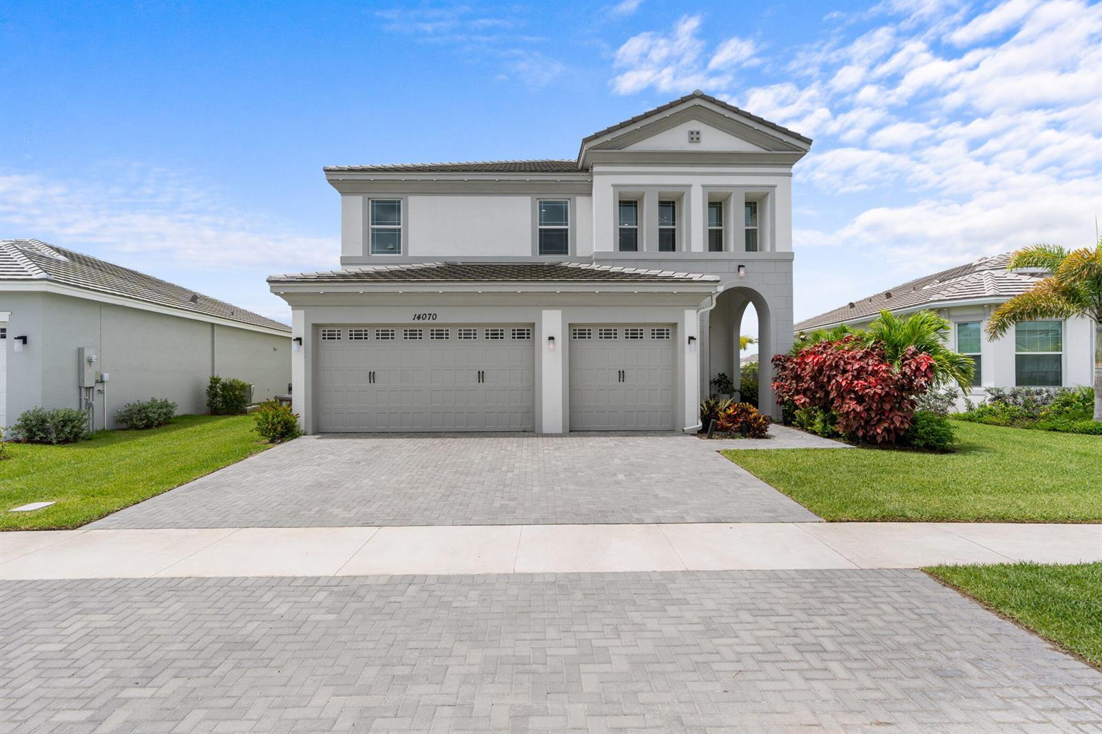 A two-story house features a gray exterior, a two-car garage, and a paved driveway — 14070 Spruce Pine Drive, Westlake FL 33470, WESTLAKE, FL