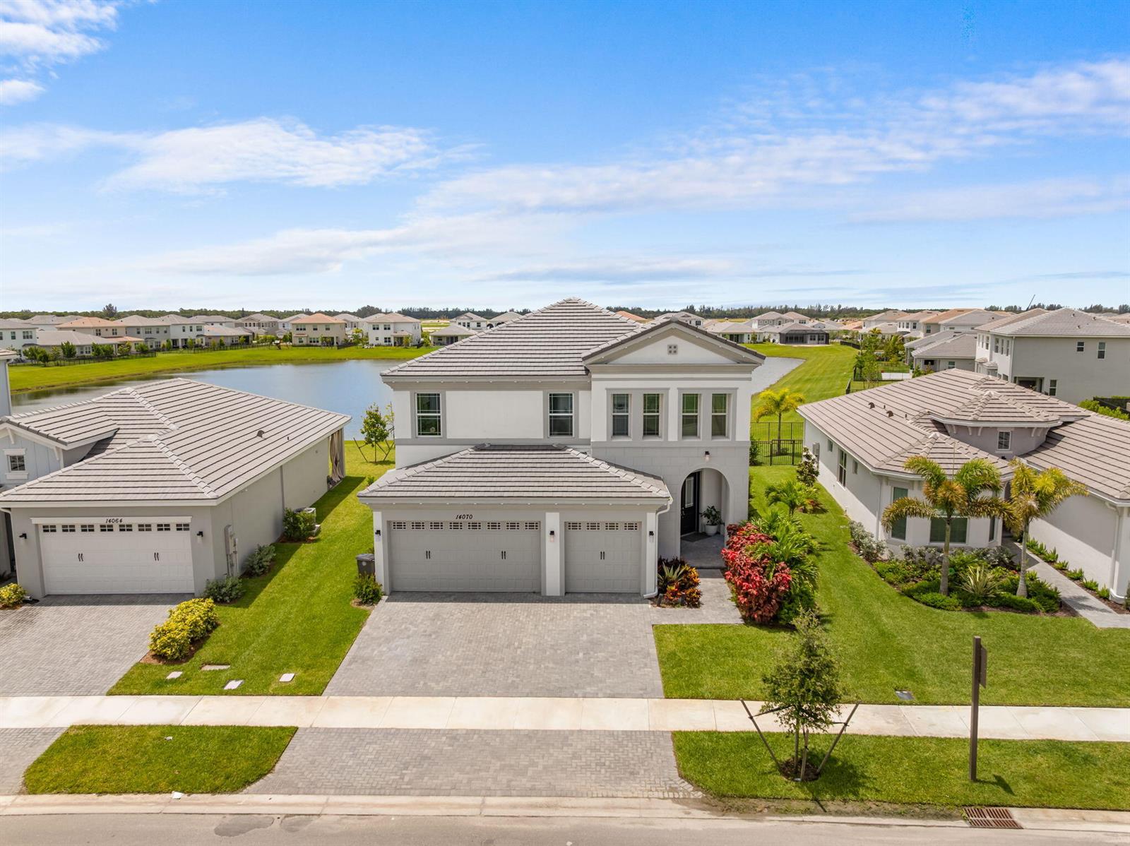 An aerial view shows a two-story suburban house with a gray tile roof and driveway — 14070 Spruce Pine Drive, Westlake FL 33470, WESTLAKE, FL