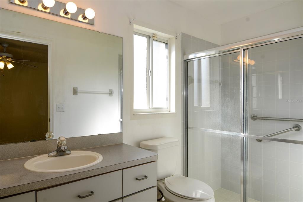 A bathroom features a vanity with a sink, a toilet, and a glass-enclosed shower — 9832 SW 61ST COURT, OCALA, FL