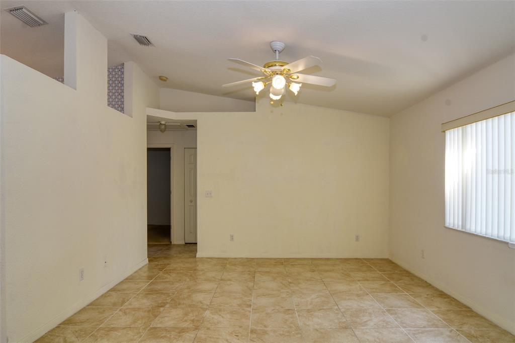 A living room features light wood flooring, a ceiling fan, and a wall-mounted television — 9832 SW 61ST COURT, OCALA, FL