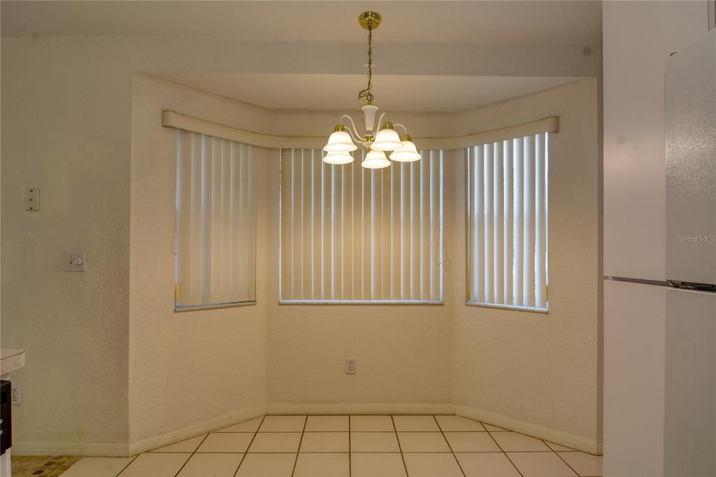 A dining nook features a bay window with vertical blinds, tile flooring, and a chandelier — 9832 SW 61ST COURT, OCALA, FL