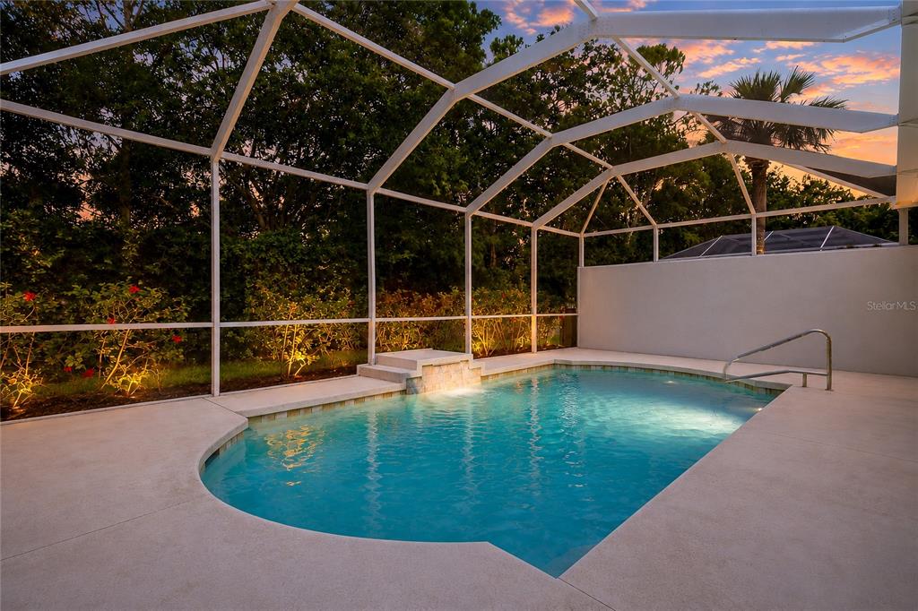 A screened-in swimming pool with a small waterfall feature sits on a concrete patio — 8644 54TH AVENUE CIRCLE E, BRADENTON, FL