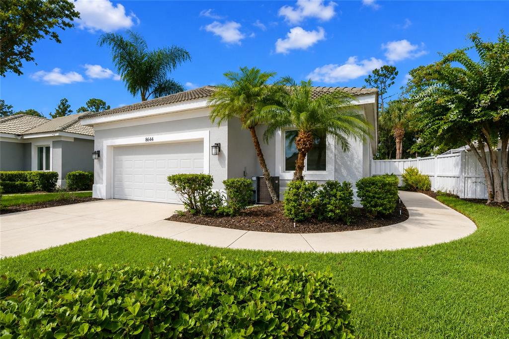 A single-story house with a white garage, palm trees, and a concrete walkway — 8644 54TH AVENUE CIRCLE E, BRADENTON, FL