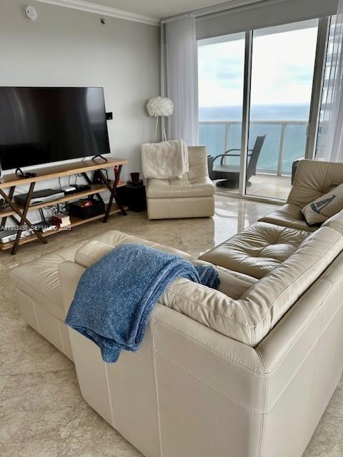A living room features a beige sectional sofa, a television on a wooden stand, and balcony — 1830 S Ocean Dr # 4006, Hallandale Beach FL 33009, HALLANDALE BEACH, FL