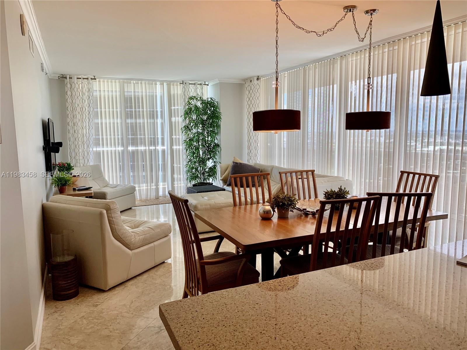A dining area and living room feature tile floors, large windows with vertical blinds, and furniture — 1830 S Ocean Dr # 4006, Hallandale Beach FL 33009, HALLANDALE BEACH, FL