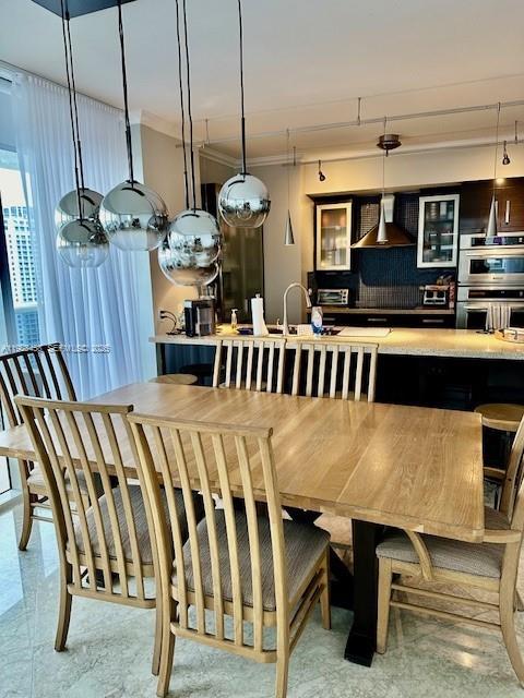A dining area with a wooden table and chairs sits before an open-concept kitchen — 1830 S Ocean Dr # 4006, Hallandale Beach FL 33009, HALLANDALE BEACH, FL