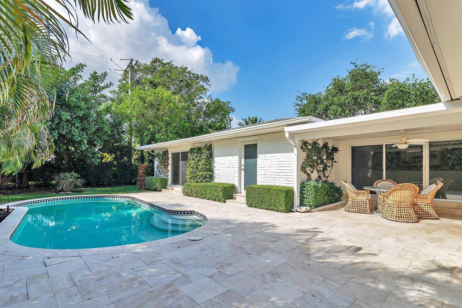 A backyard features a swimming pool, stone patio, and a white brick house with a patio — 246 Gray Street, West Palm Beach FL 33405, WEST PALM BEACH, FL