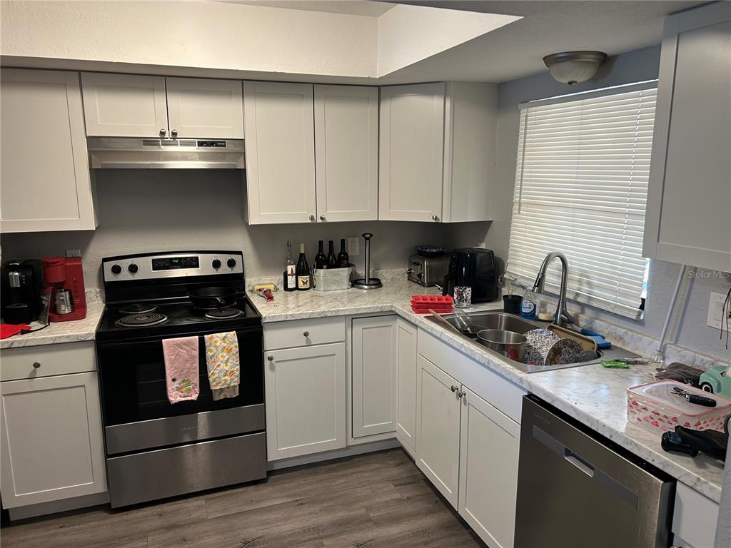 A kitchen features white cabinets, a black stove, a stainless steel dishwasher, and marble-patterned countertops — 6301 58TH STREET N UNIT 705, PINELLAS PARK, FL