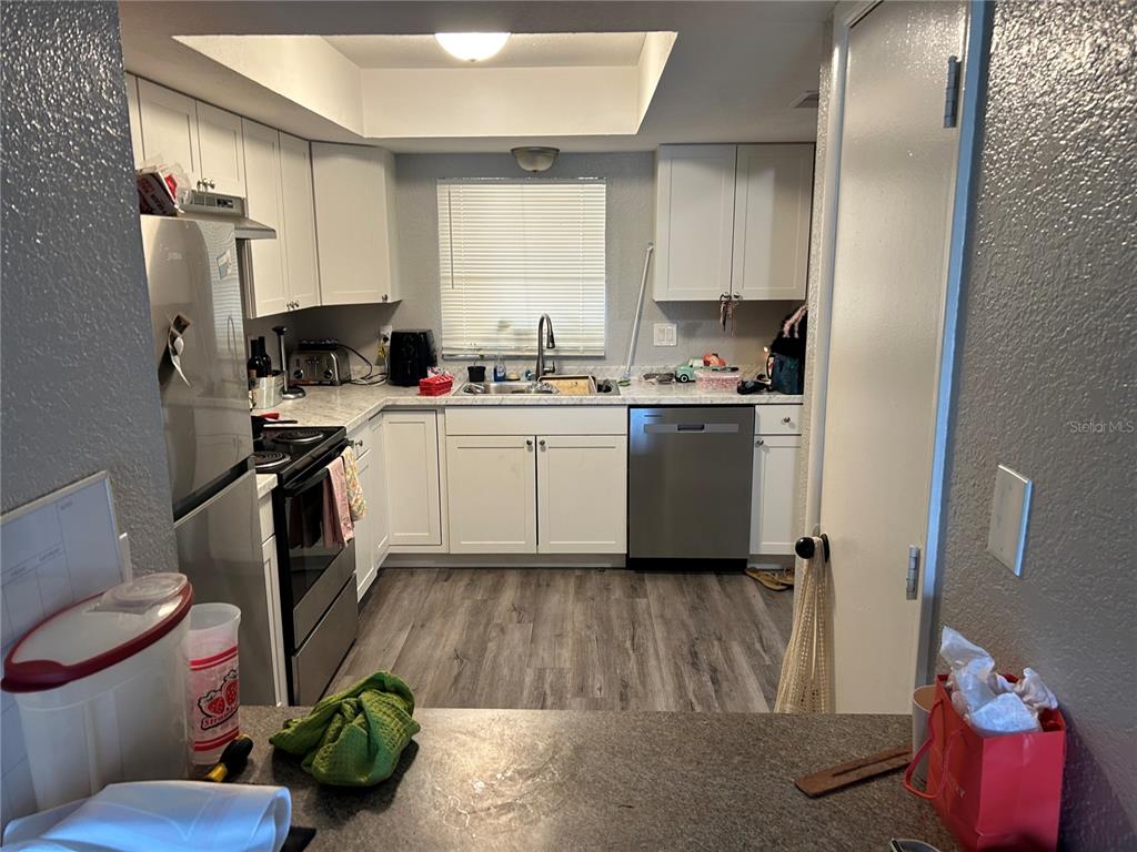 A kitchen features white cabinets, stainless steel appliances, a window, and wood-look flooring — 6301 58TH STREET N UNIT 705, PINELLAS PARK, FL