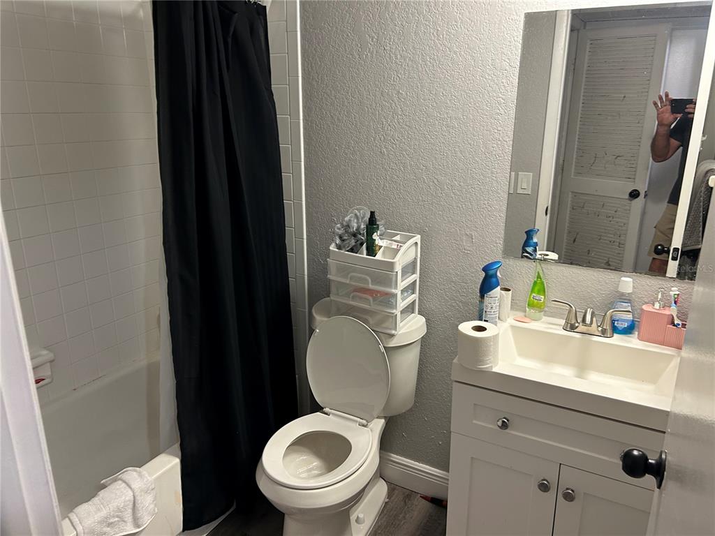 A bathroom features a white vanity, a toilet, and a shower-tub combination with a black curtain — 6301 58TH STREET N UNIT 705, PINELLAS PARK, FL