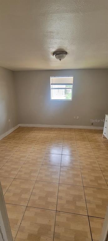 An empty room with light-colored tile flooring, a single window, and a ceiling light fixture — 4204 N MANHATTAN AVENUE, TAMPA, FL