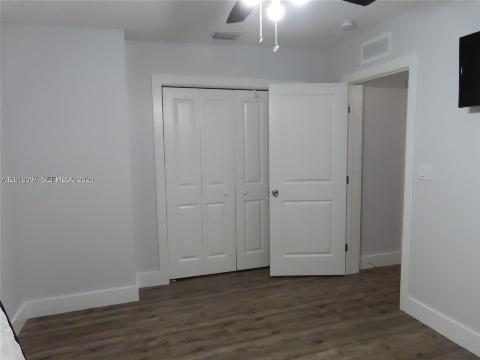 A room features light gray walls, wood-look flooring, a white closet, and an open doorway — 2433 NW 96th St # B, Miami FL 33147, MIAMI, FL