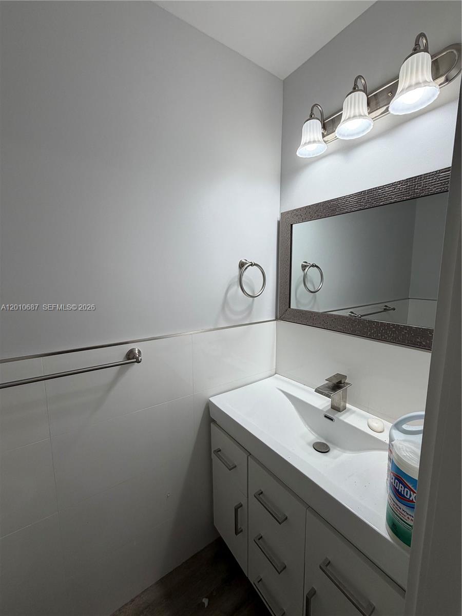 A modern bathroom features a white vanity, a rectangular mirror, and a three-light fixture — 2433 NW 96th St # B, Miami FL 33147, MIAMI, FL