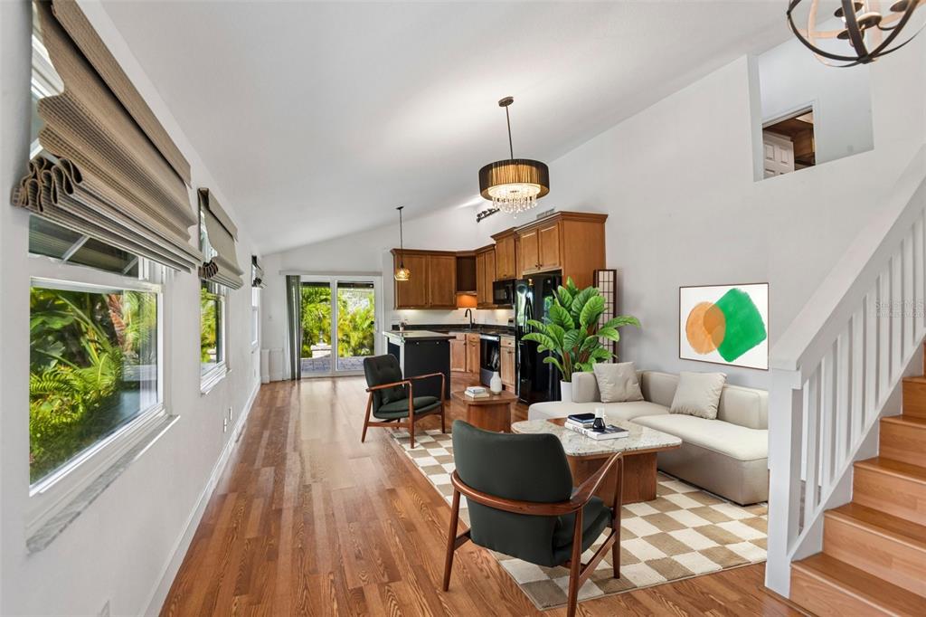 An open-concept living room and kitchen featuring hardwood floors, a staircase, and sliding glass doors — 5731 28TH AVENUE S, GULFPORT, FL