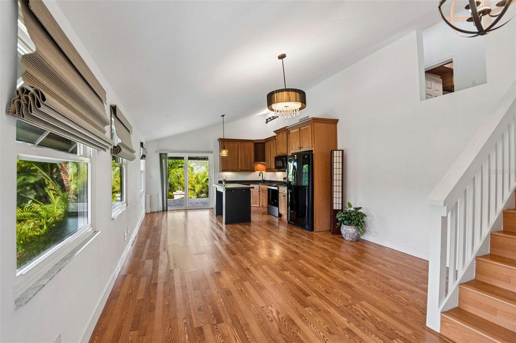 A kitchen with wood cabinets and a black island opens to a living area with stairs — 5731 28TH AVENUE S, GULFPORT, FL