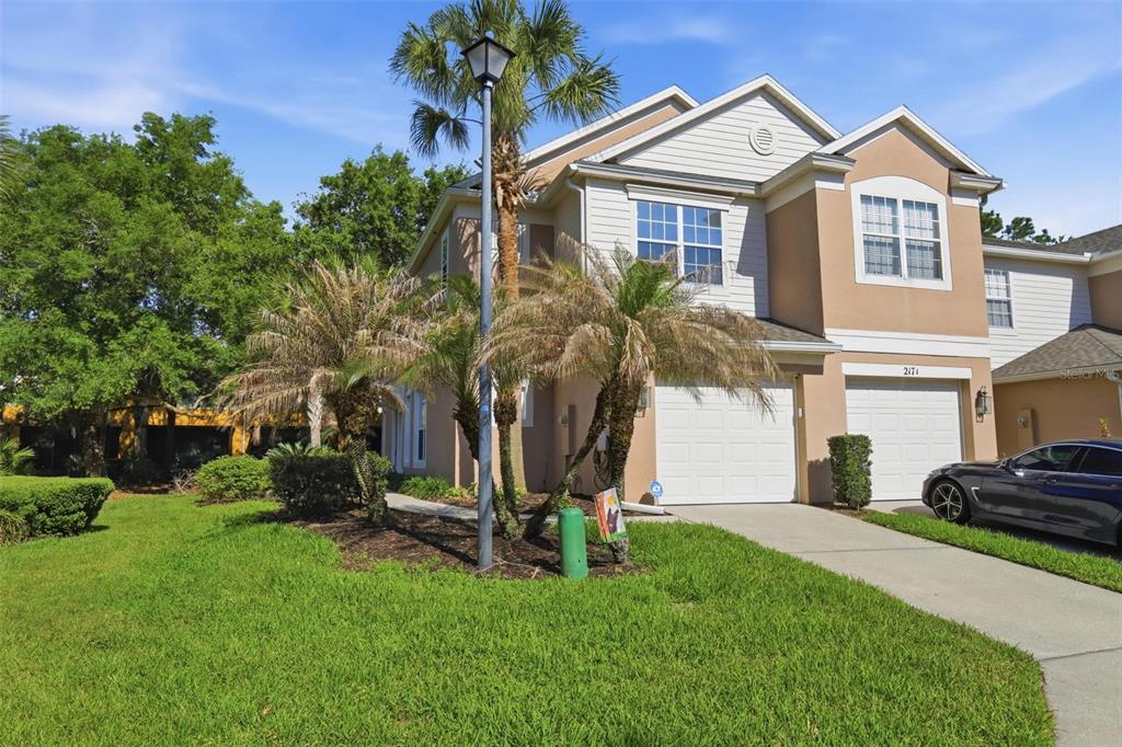 A two-story tan townhouse with a two-car garage and a front lawn with palm trees — 2181 STOCKTON DRIVE, SANFORD, FL
