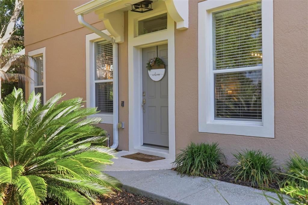 The exterior of a tan house features a gray front door with a welcome wreath — 2181 STOCKTON DRIVE, SANFORD, FL