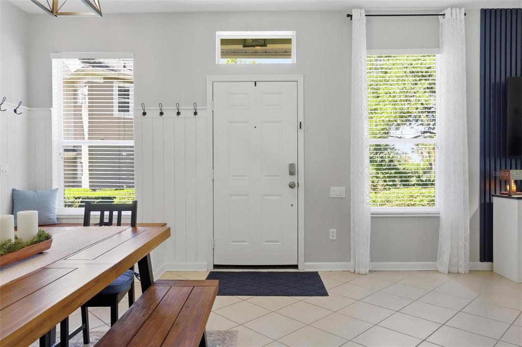 A dining area features a wooden table, bench seating, a white front door, and tiled floors — 2181 STOCKTON DRIVE, SANFORD, FL