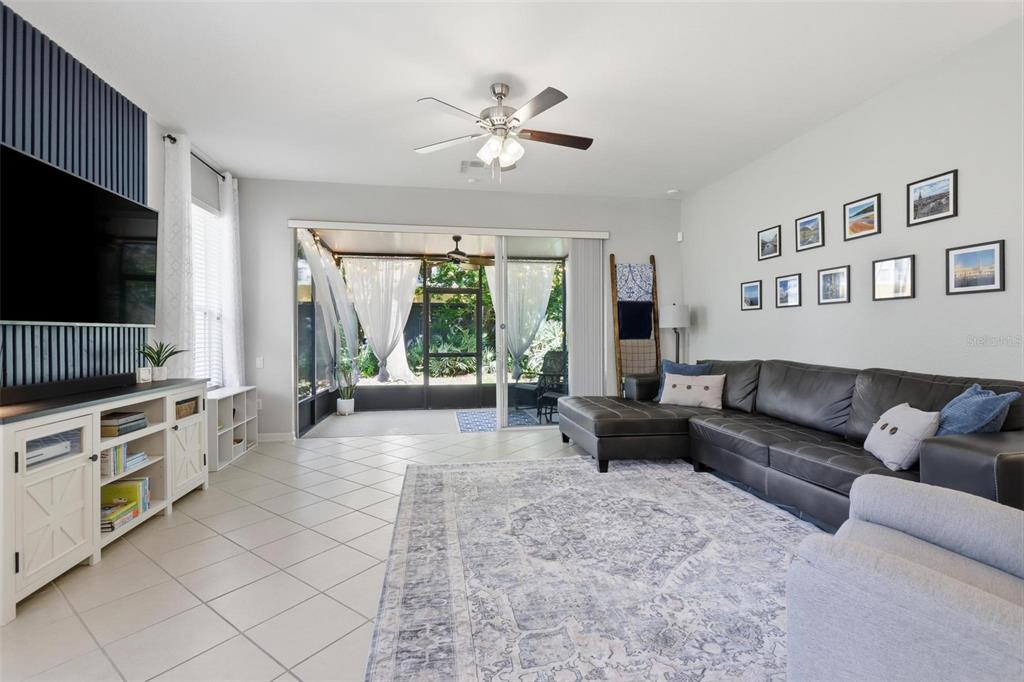 A living room features a dark leather sectional, a patterned area rug, and a sliding door — 2181 STOCKTON DRIVE, SANFORD, FL
