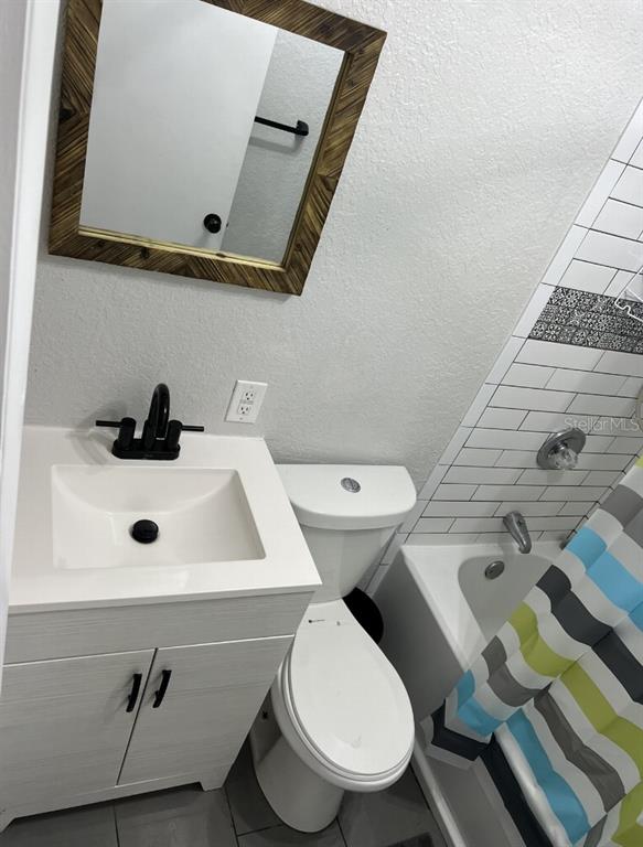 A small bathroom features a white vanity, a toilet, and a tiled shower-tub combination — 10015 LINDA STREET, GIBSONTON, FL