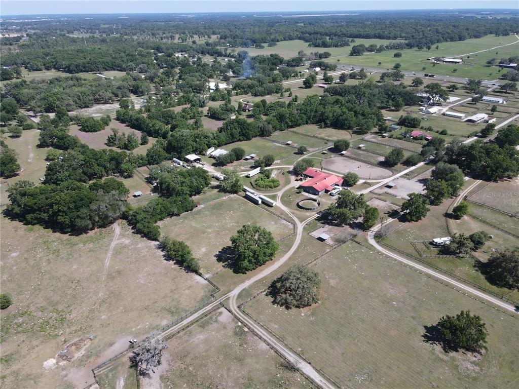 An aerial view shows a rural property with a red-roofed barn, pastures, and trees — 311 NW 106TH AVENUE, OCALA, FL