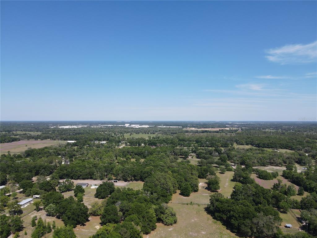 An aerial view shows a large, rural landscape with scattered trees, pastures, and distant buildings — 311 NW 106TH AVENUE, OCALA, FL
