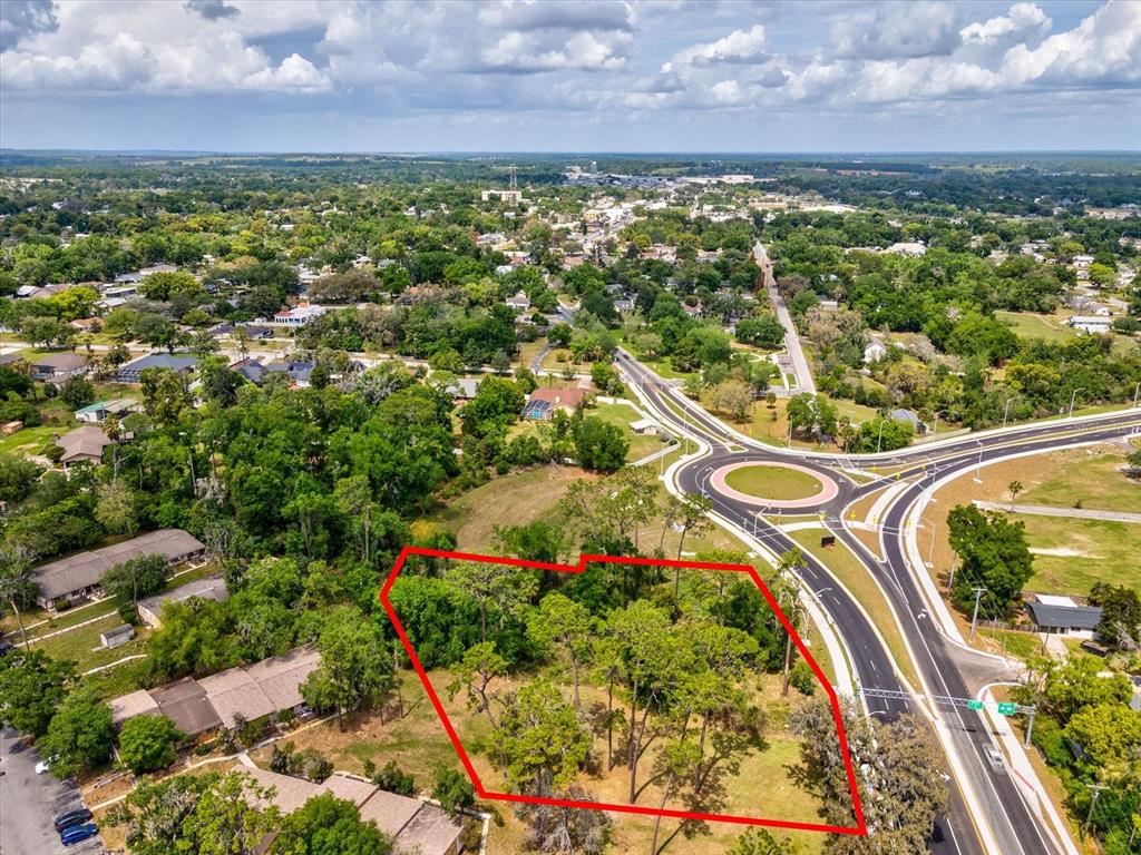 An aerial view shows a vacant, tree-covered lot outlined in red next to a roundabout — STATE RD 98, DADE CITY, FL