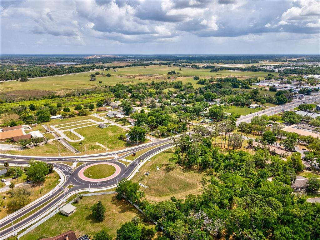 An aerial view shows a roundabout at a road intersection surrounded by trees and fields — STATE RD 98, DADE CITY, FL