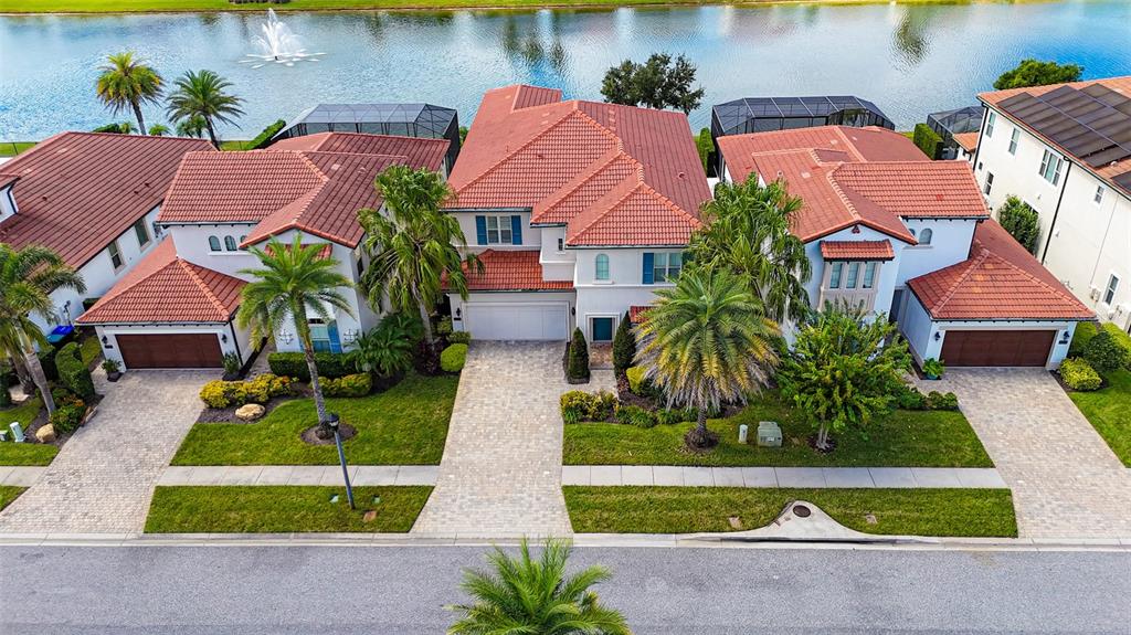 An aerial view shows three large houses with red tile roofs facing a lake — 10751 ROYAL CYPRESS WAY, ORLANDO, FL