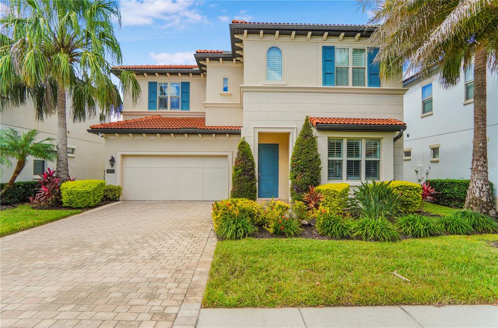 A two-story Mediterranean-style house with a tiled roof, blue shutters, and a paved driveway — 10751 ROYAL CYPRESS WAY, ORLANDO, FL