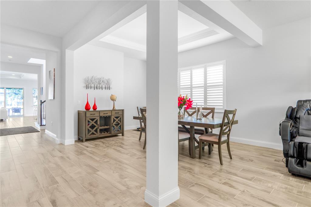 A dining area with wood-look tile flooring, a central column, and a wooden sideboard — 10751 ROYAL CYPRESS WAY, ORLANDO, FL