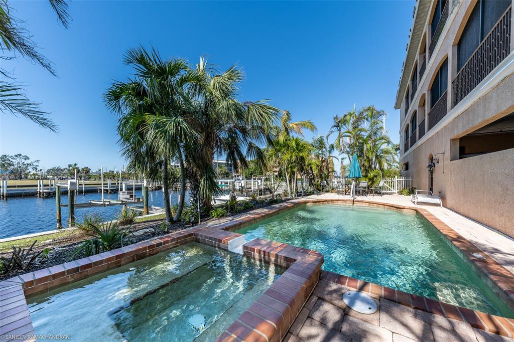 A swimming pool and attached hot tub sit beside a building overlooking a boat dock — 290 LEWIS CIRCLE UNIT 131, PUNTA GORDA, FL