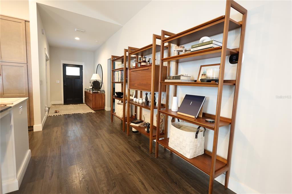 A bright living room features a large sectional sofa, two modern chairs, and dark flooring — 655 12TH AVENUE S, ST PETERSBURG, FL