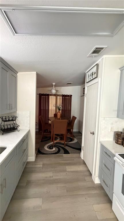 A kitchen with gray cabinets and white countertops leads into a dining area with wood furniture — 747 ISLAND STREET, DAVENPORT, FL