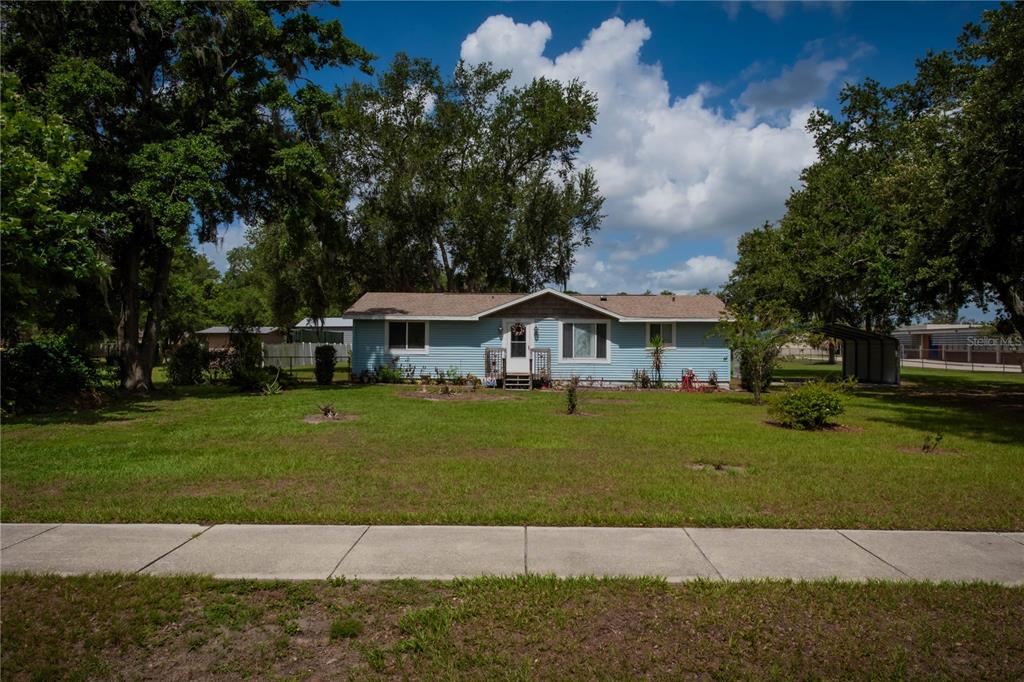 A light blue single-story house sits on a grassy lot with mature trees — 5015 TURKEY CREEK ROAD, PLANT CITY, FL