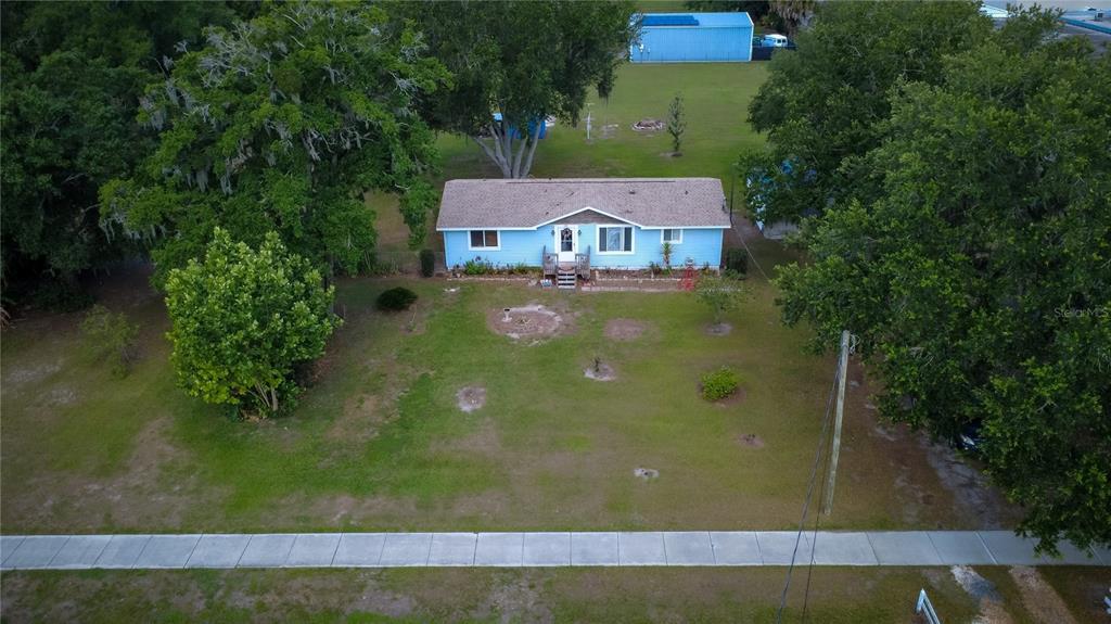 An aerial view shows a light blue house with a brown roof on a grassy lot — 5015 TURKEY CREEK ROAD, PLANT CITY, FL