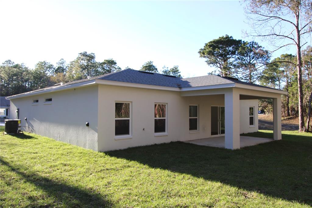 A single-story house with a white stucco exterior, a two-car garage, and a shingled roof — 9719 N SANDREE DRIVE, CITRUS SPRINGS, FL