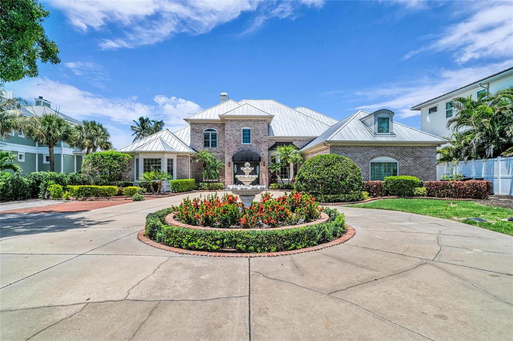 A brick house with a metal roof features a circular driveway and a central fountain — 7708 DESOTO MEMORIAL HIGHWAY, BRADENTON, FL