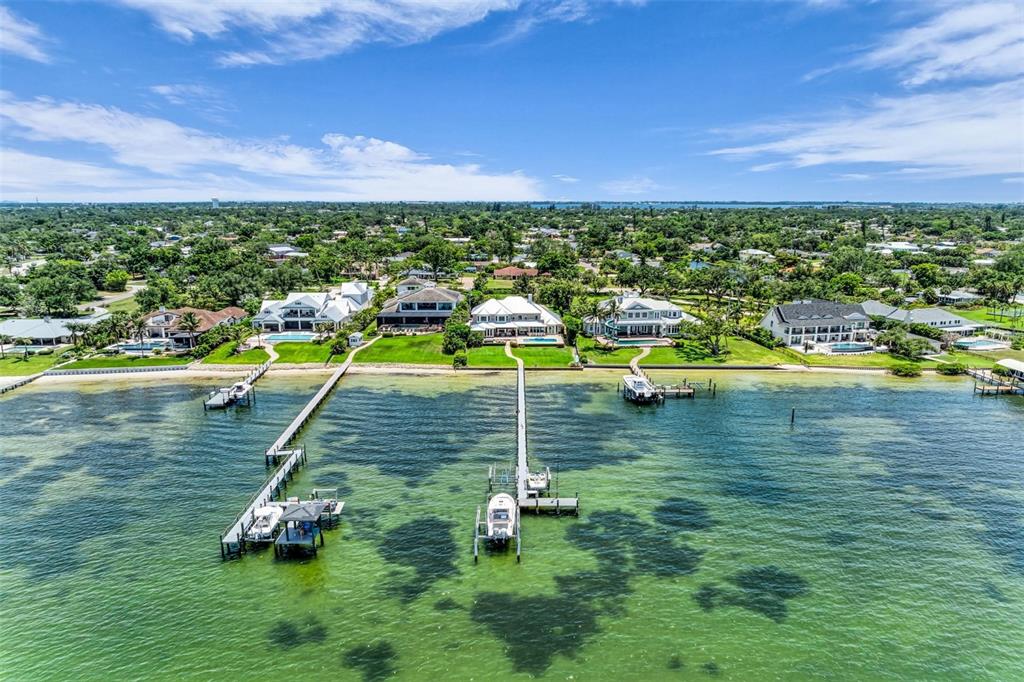 An aerial view of waterfront homes with private docks extending into the shallow bay — 7708 DESOTO MEMORIAL HIGHWAY, BRADENTON, FL