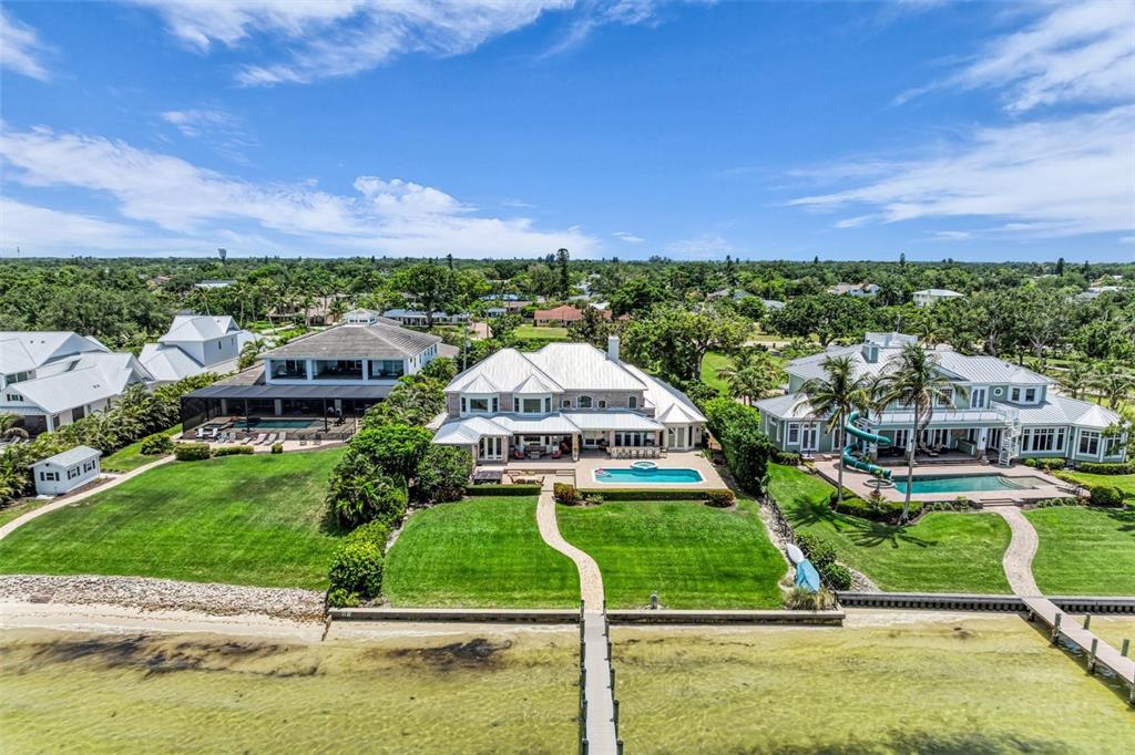 An aerial view of three waterfront houses with swimming pools and private docks — 7708 DESOTO MEMORIAL HIGHWAY, BRADENTON, FL