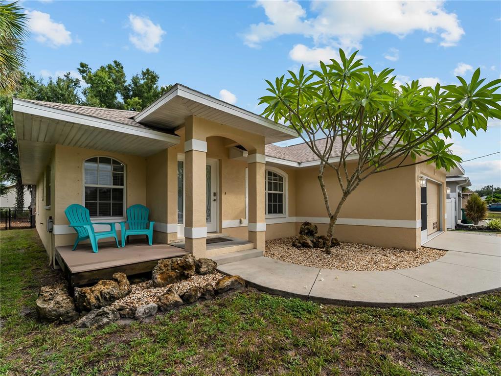 A single-story house with a tan exterior, a front porch, and a small tree — 145 CREVALLE ROAD, ROTONDA WEST, FL