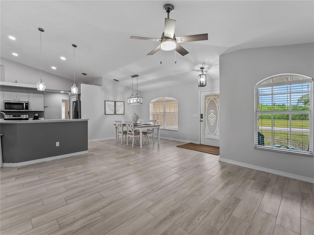 An open-concept living and dining area features light wood-look flooring and a ceiling fan — 145 CREVALLE ROAD, ROTONDA WEST, FL