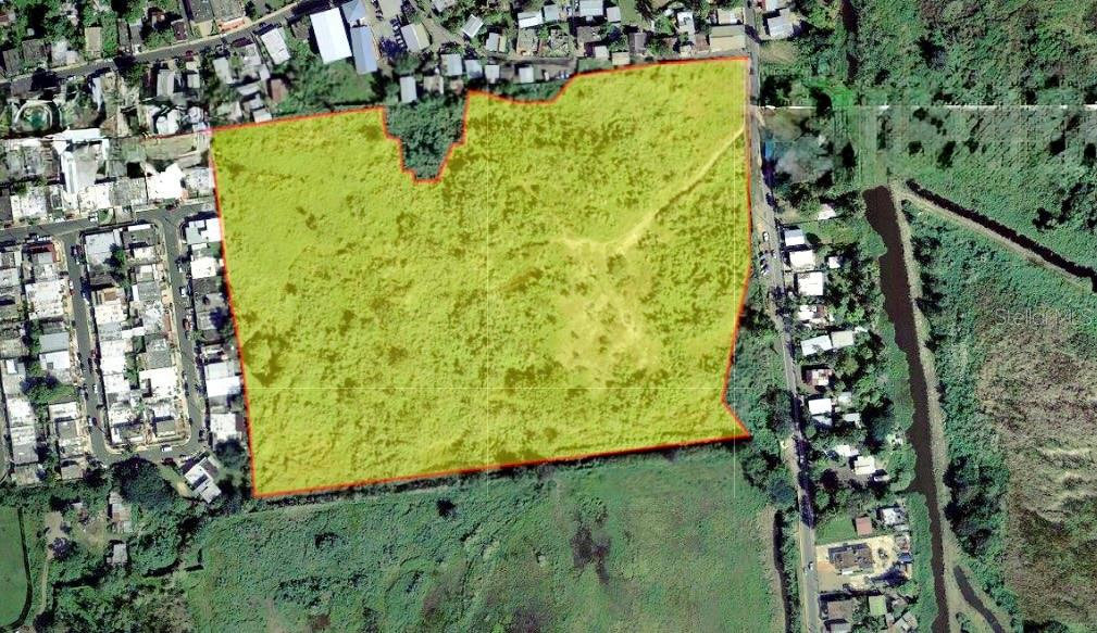 An aerial view shows a large, yellow-highlighted vacant plot of land bordered by residential streets — PR-8869 AT KILOMETER 0.7, PALMAS WARD, CAT, CATANO, PR