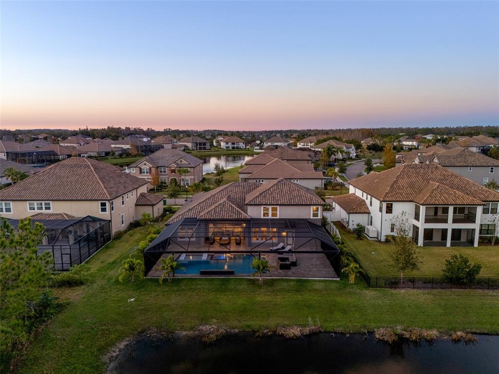 An aerial view of a suburban house with a screened-in pool and a backyard pond — 33376 KATELAND DRIVE, WESLEY CHAPEL, FL