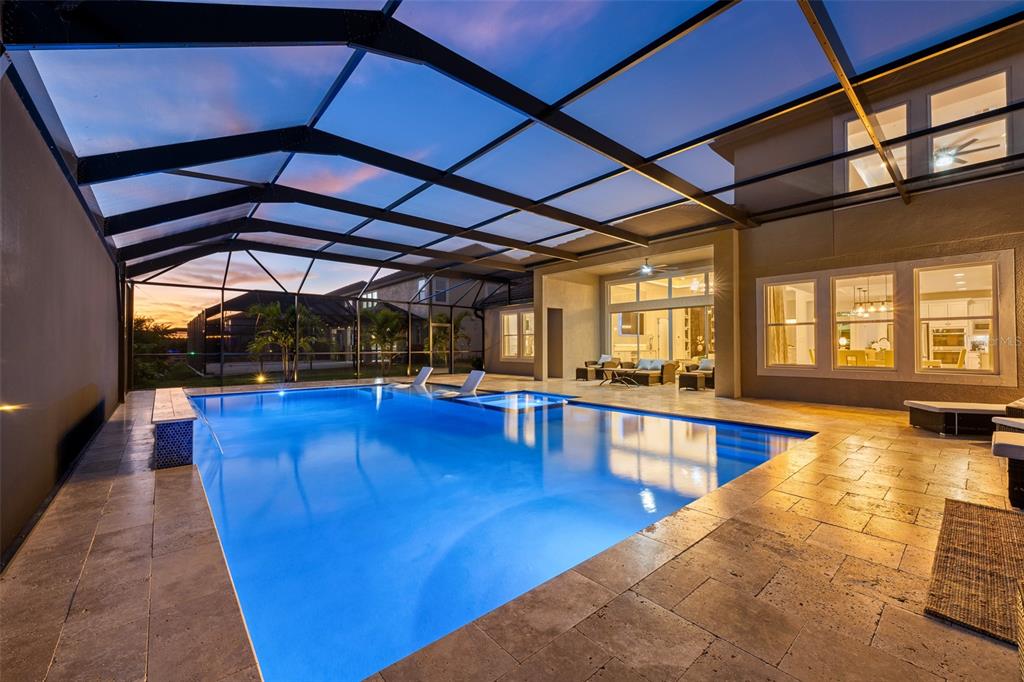 A swimming pool with a screened enclosure sits on a patio next to a house — 33376 KATELAND DRIVE, WESLEY CHAPEL, FL