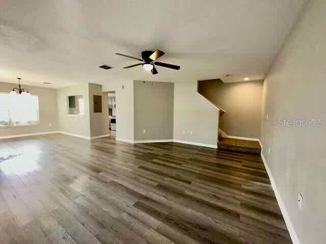 An open-concept living area features wood-look flooring, a ceiling fan, and a staircase — 6335 MAISIE ROAD, ZEPHYRHILLS, FL