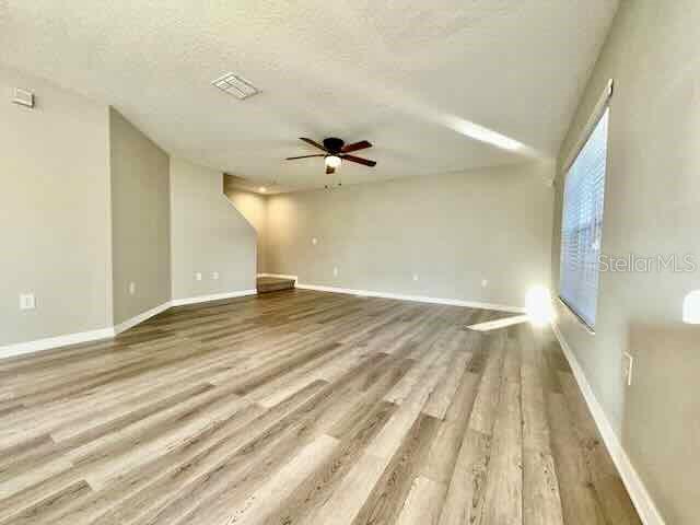 An empty room features light wood-look flooring, neutral walls, and a ceiling fan — 6335 MAISIE ROAD, ZEPHYRHILLS, FL
