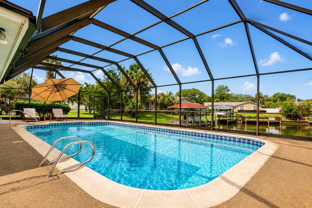 A screened-in swimming pool overlooks a canal with a dock and boat lift — 31 FLEMING COURT, PALM COAST, FL