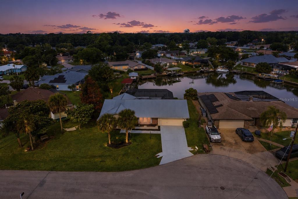 An aerial view shows a single-story house with a metal roof and a waterfront backyard — 31 FLEMING COURT, PALM COAST, FL