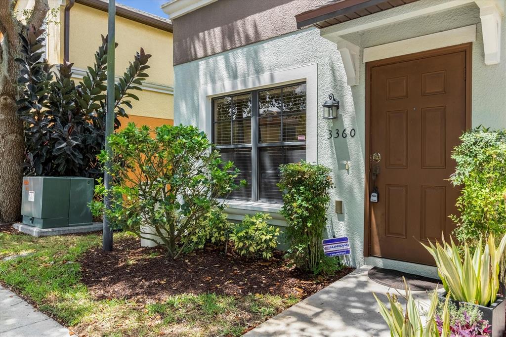 The exterior of a house features a brown door, a window, and landscaping — 3360 WINDLESHORE WAY, SANFORD, FL